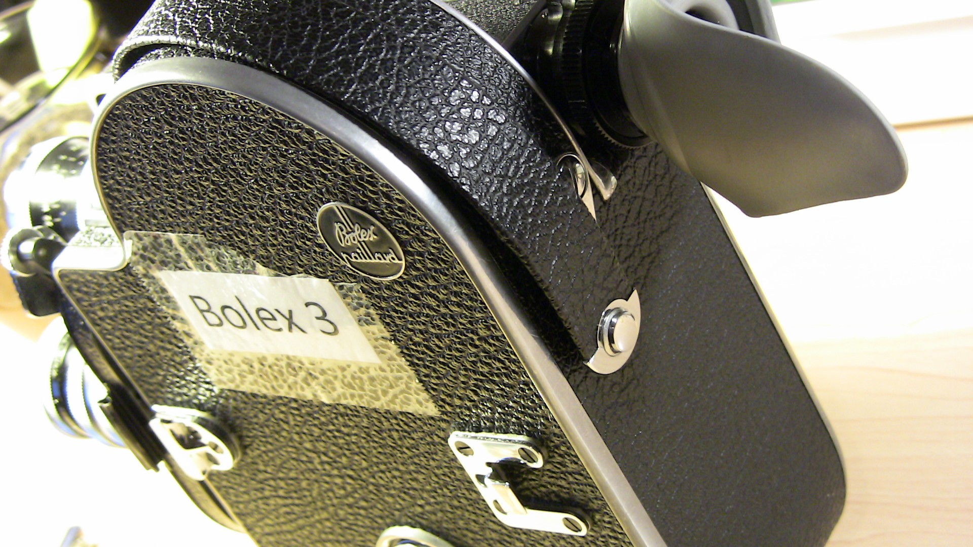 Image of close-up of a vintage bolex paillard 16mm film camera, showcasing its classic black leather textured casing and winding handle. this iconic piece of filmmaking equipment is favored for its durability and precision, making it a popular choice among film enthusiasts and