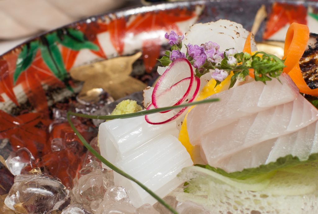 Image of this image showcases a beautifully plated japanese sashimi dish, featuring fresh cuts of raw fish, delicate slices of radish, and vibrant edible flowers. set against a traditional ornate japanese plate, it highlights culinary artistry and gourmet seafood presentation. perfect for keywords like