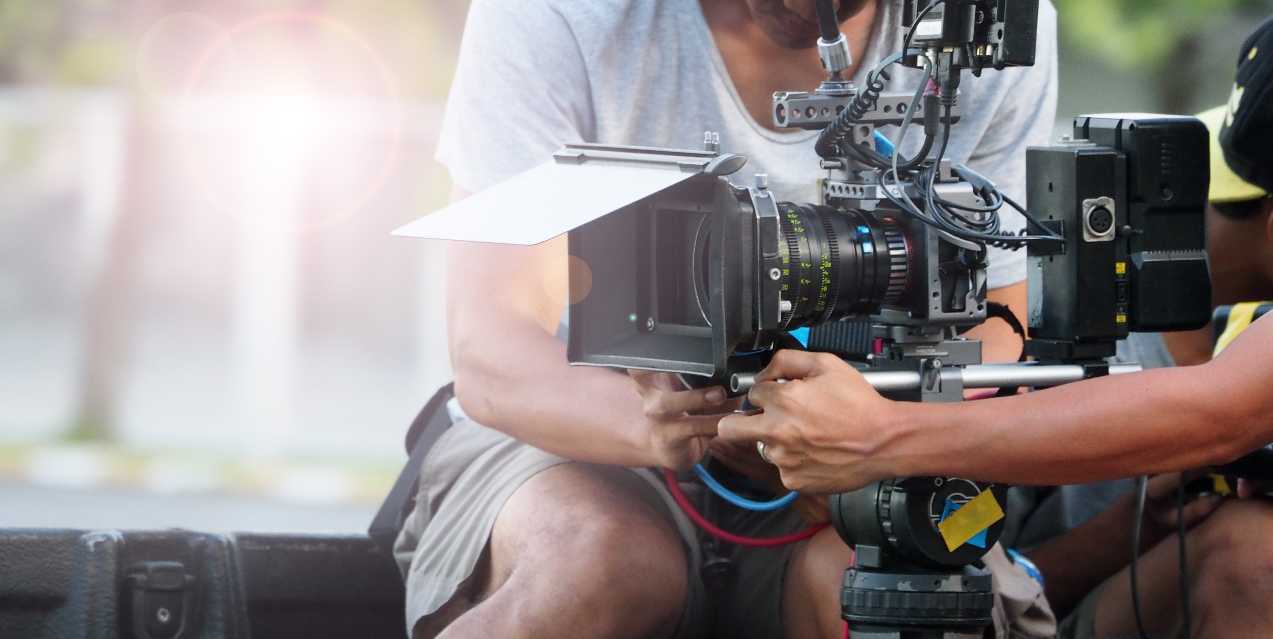 Image of film crew setting up professional video camera outdoors. close-up of a high-quality camera with lens hood and cables, operated by technicians. behind-the-scenes shot ideal for keywords like film production, video equipment, camera setup, and outdoor filming.