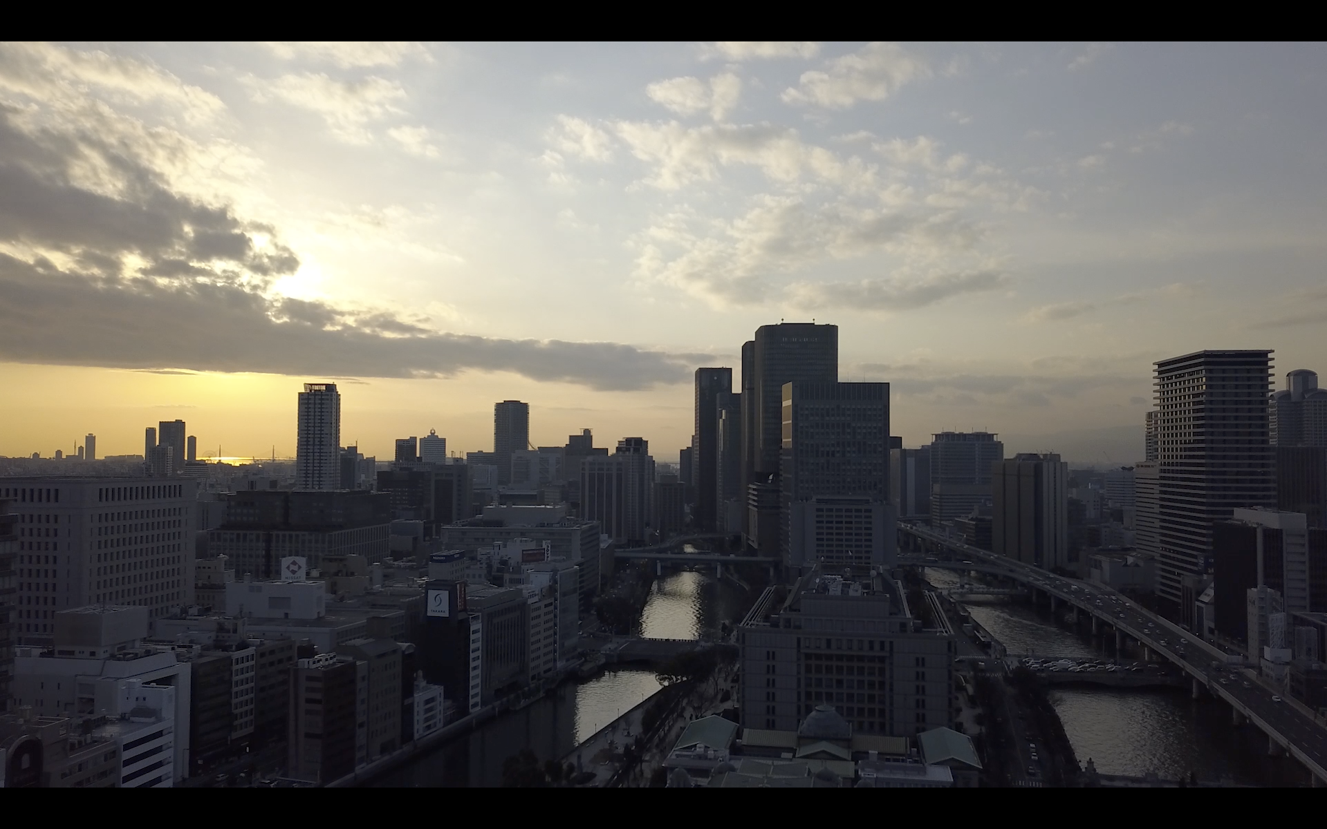 Image of cityscape of osaka, japan, showcasing a stunning sunset above the skyline with modern skyscrapers and a river. the image captures the bustling energy and architectural beauty of osaka, highlighting vibrant urban life and scenic views ideal for travel enthusiasts.