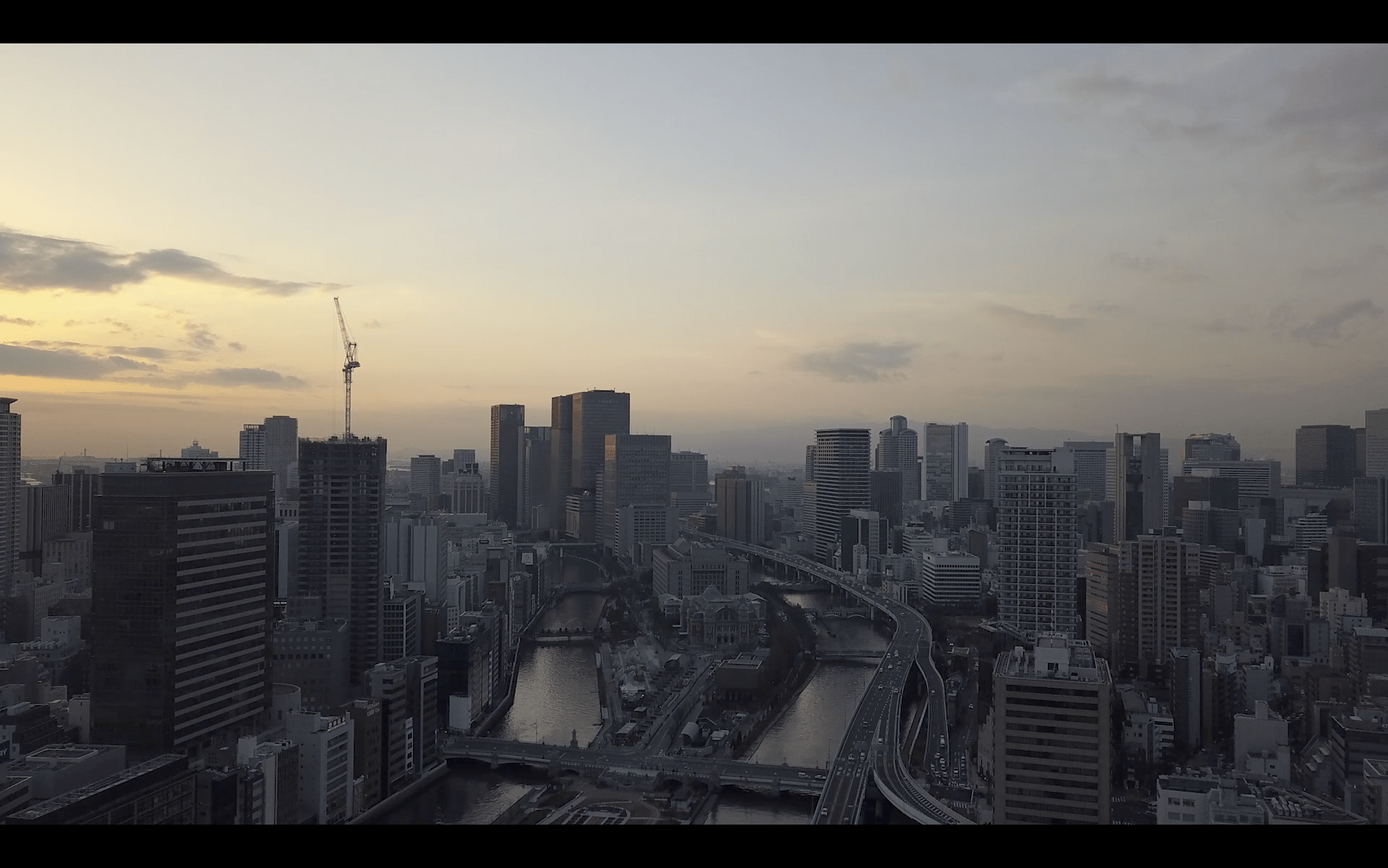 Image of skyline of a bustling city at dusk, featuring a network of bridges and skyscrapers under an expansive sky. the urban landscape highlights modern architecture, intersecting waterways, and a serene sunset, perfect for showcasing metropolitan beauty and cityscape photography.