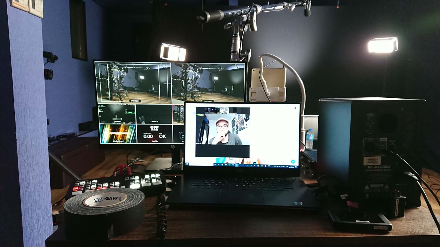 Image of a professional streaming setup featuring dual monitors, a laptop, and advanced audio equipment. the scene displays video editing software, lighting kits, and various tech devices essential for live broadcasting or video conferencing. ideal for content creators and digital media professionals seeking to optimize their