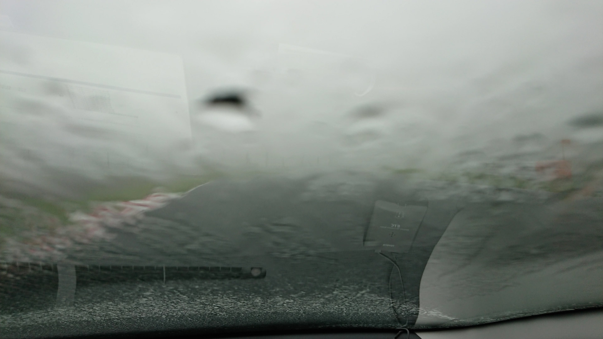 Image of blurry windshield in heavy rain, obscuring the driver's view. raindrops and water streaks create a distorted effect, highlighting bad weather conditions and driving challenges during a storm. perfect depiction of rainy day commute and road safety.