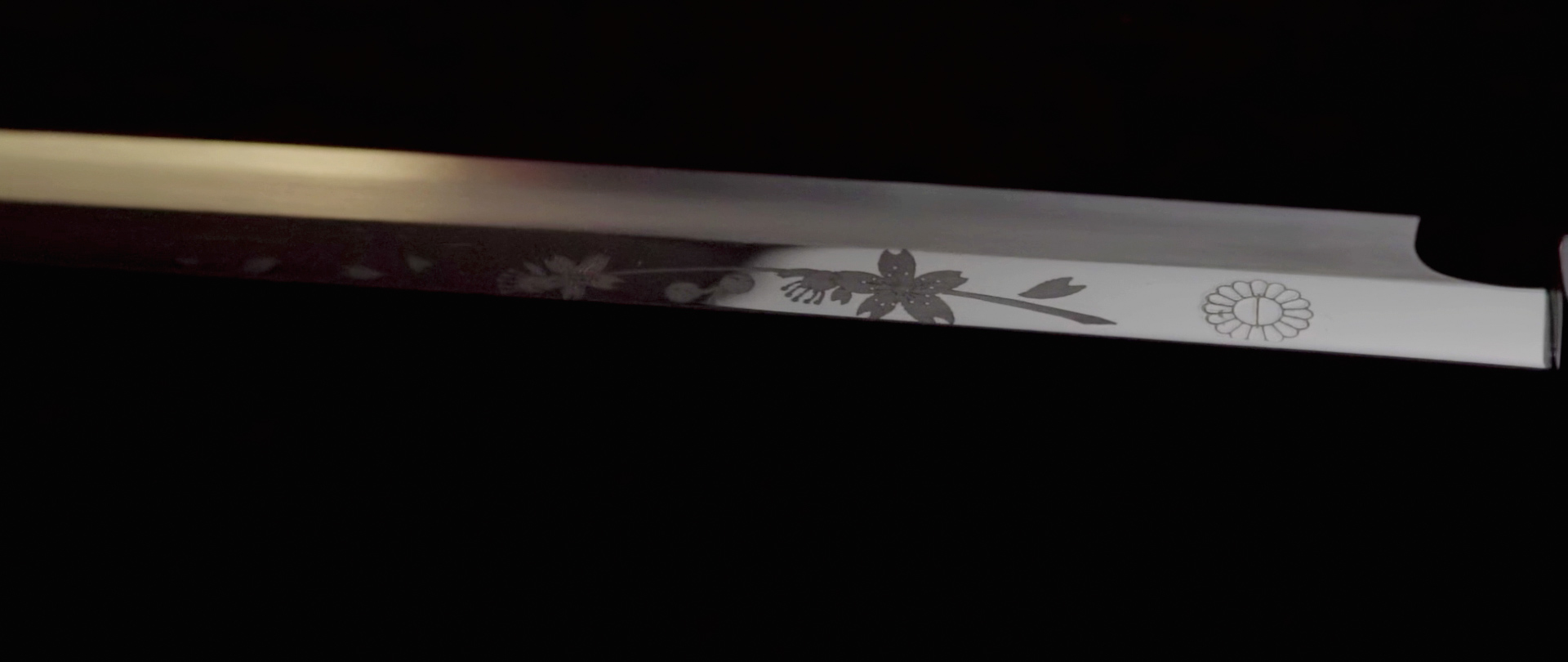 Image of this image showcases a traditional japanese katana blade with intricate floral engravings. the polished steel reflects light, highlighting the detailed cherry blossom designs. featuring expert craftsmanship, this sword epitomizes japanese artistry and precision in sword-making. ideal for enthusiasts of japanese