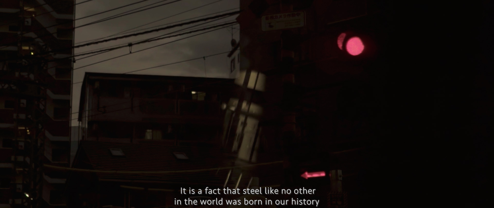 Image of urban night scene featuring a dimly lit street with buildings silhouetted against a dark sky. a red traffic light glows prominently, while power lines crisscross the view. the scene is accompanied by the text, "it is a fact that steel