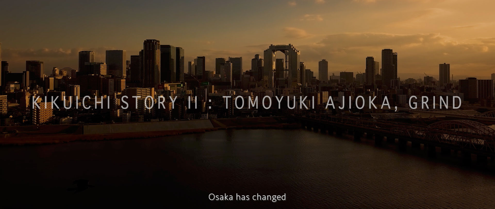 Image of sunset over the osaka skyline features prominently in this image highlighting "kikuichi story ii: tomoyuki ajioka, grind." the cityscape is bathed in a warm golden glow, showcasing the architectural marvels and urban beauty of osaka