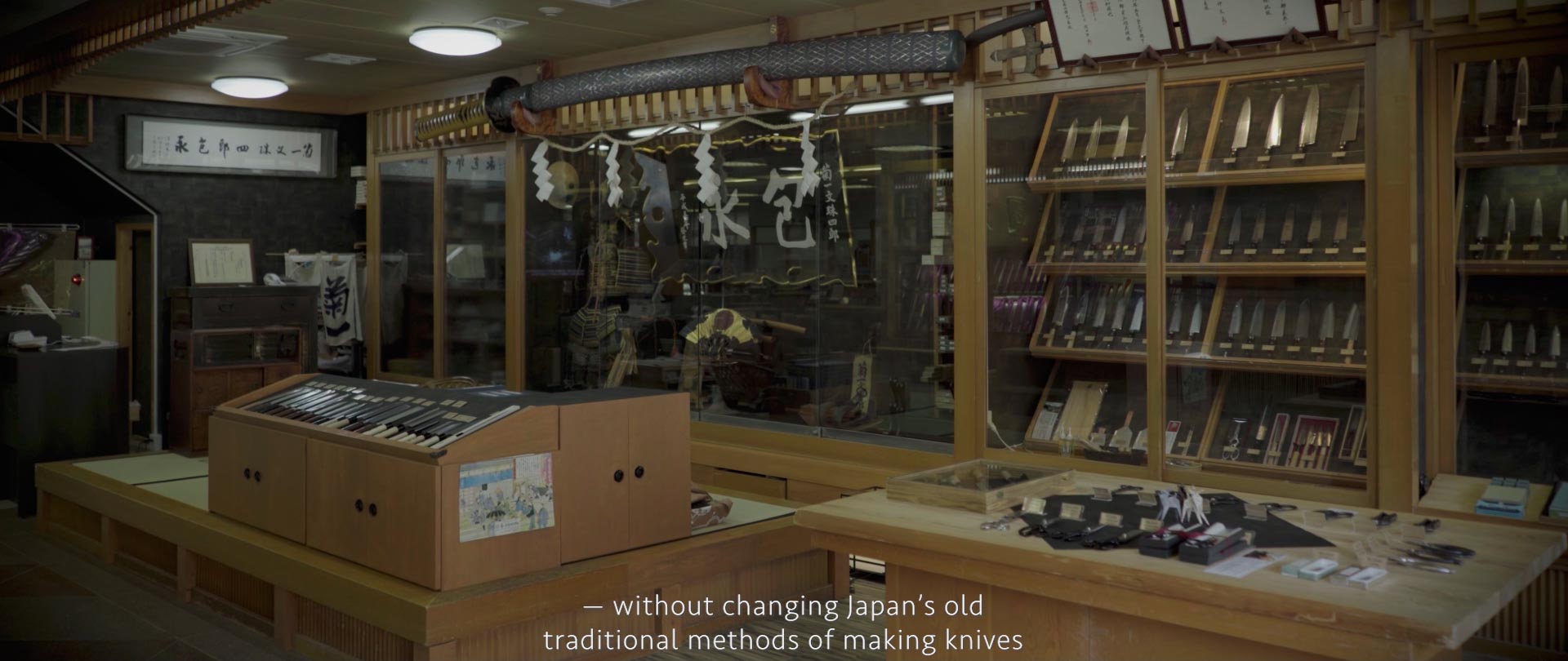 Image of a traditional japanese cutlery shop interior displaying an array of handcrafted knives. the wooden shelves are meticulously arranged, showcasing the precision and artistry of knife-making in japan. a large sword decorates the upper area, adding cultural significance. the space reflects japan's
