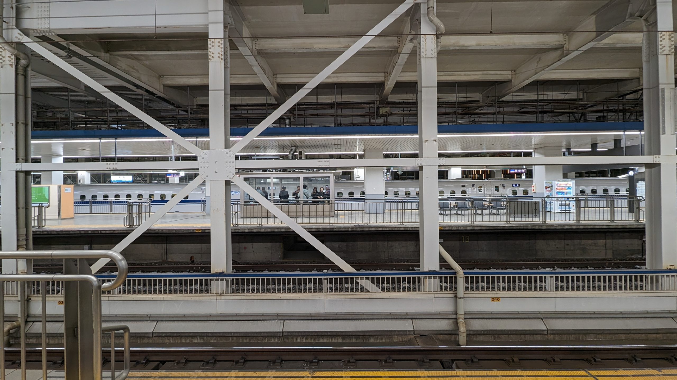 Image of a bustling train station interior featuring modern architecture with metal beams and platforms. visible are tracks and a stationary bullet train, typical of japanese transportation infrastructure. the scene captures the organized, efficient atmosphere of a high-speed rail hub, ideal for travelers and commuters in