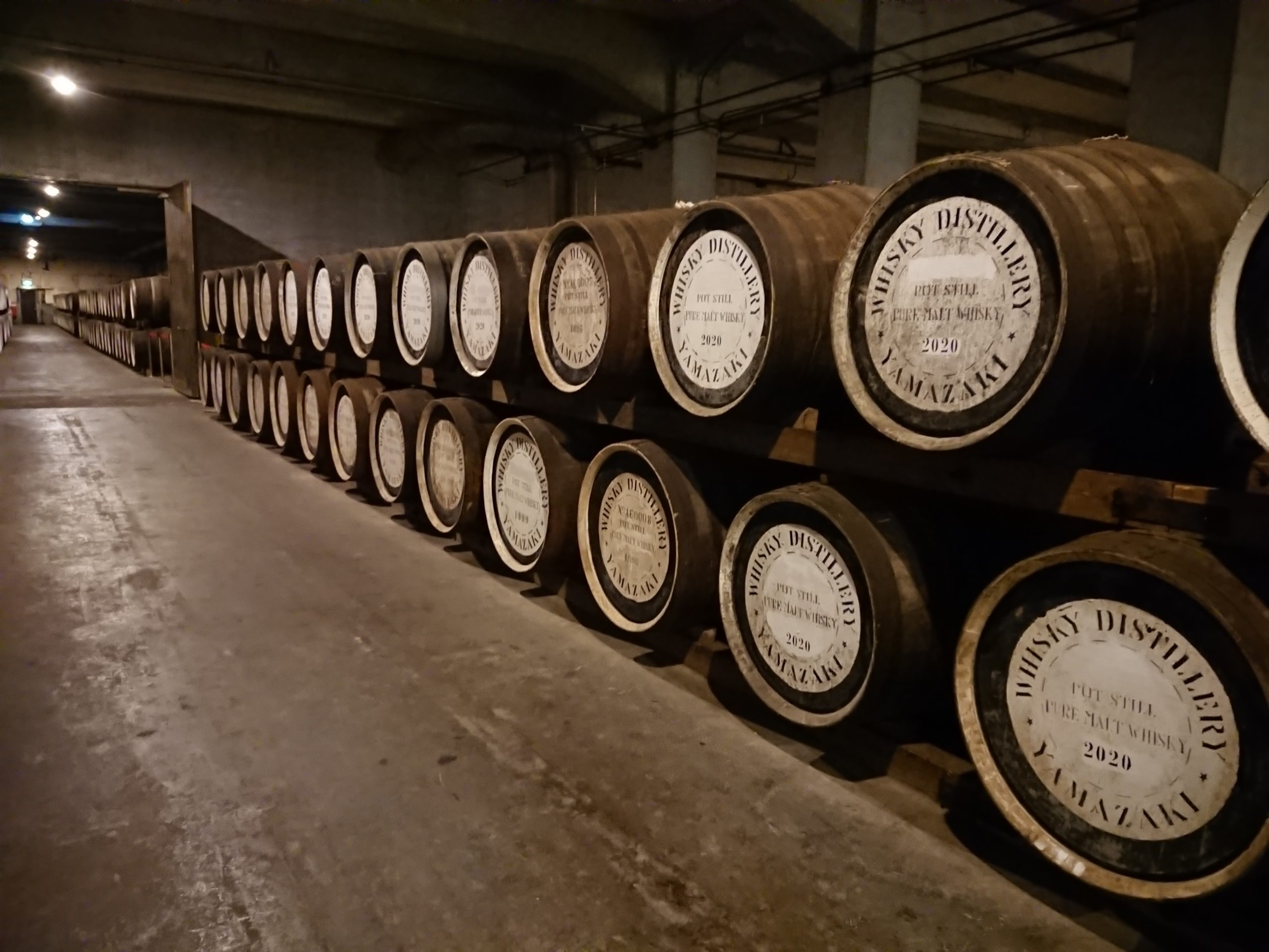 A cinematic image showcasing the contrast between Tokyo's modern skyline and the traditional landscapes of Kansai, highlighting the House of Suntory's whisky-making process.